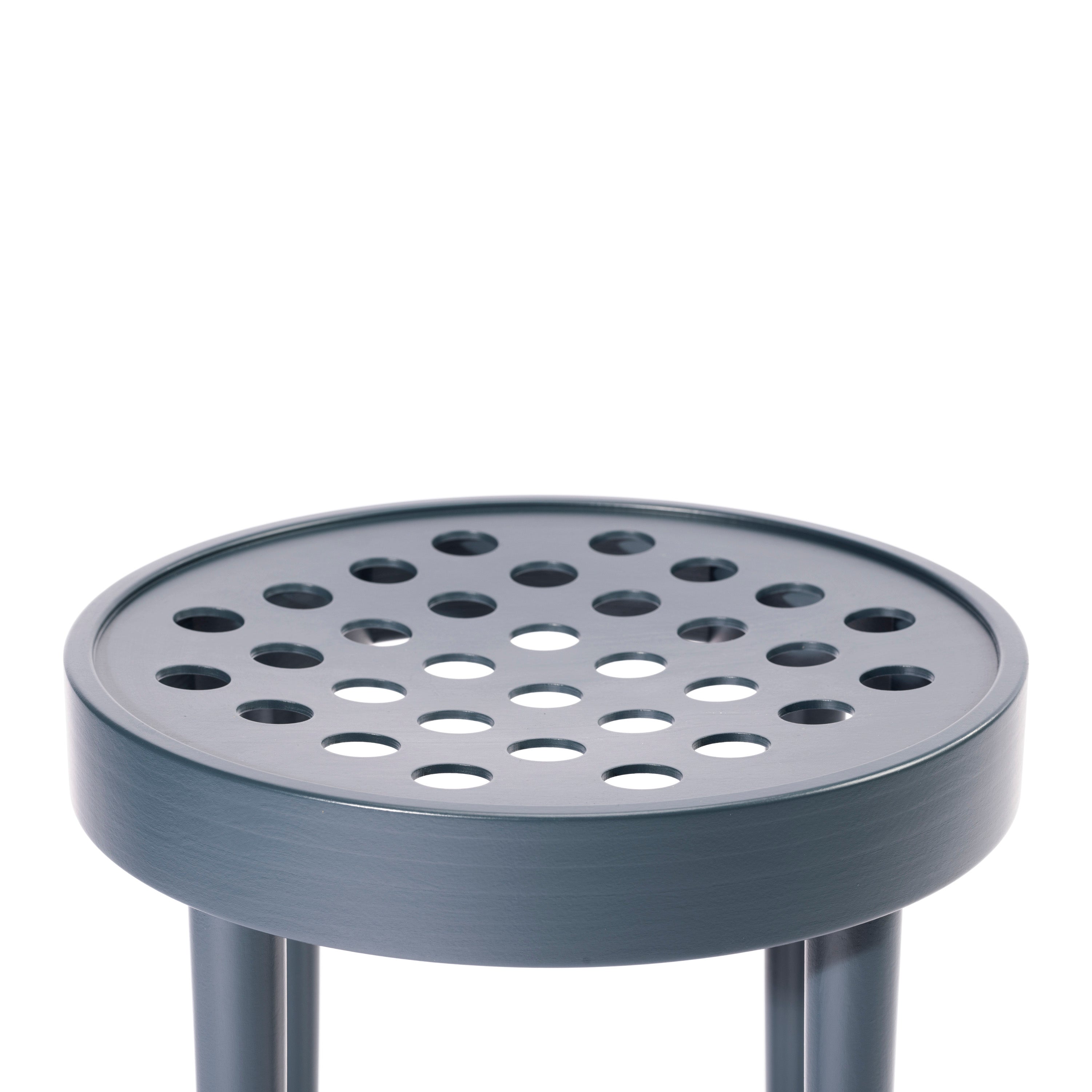 The Stool 822 by TON, designed by Claesson Koivisto Rune, features a gray metal seat with circular holes and a sleek three-legged design, embodying Scandinavian minimalism in every detail.