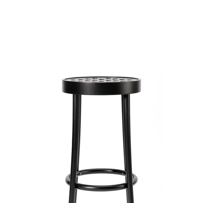 The Barstool 822 by TON showcases Scandinavian minimalism with a sleek black metal frame. Its circular seat features perforated holes, and the simple four-leg design is enhanced by a circular footrest, exuding refined elegance against a plain white backdrop.