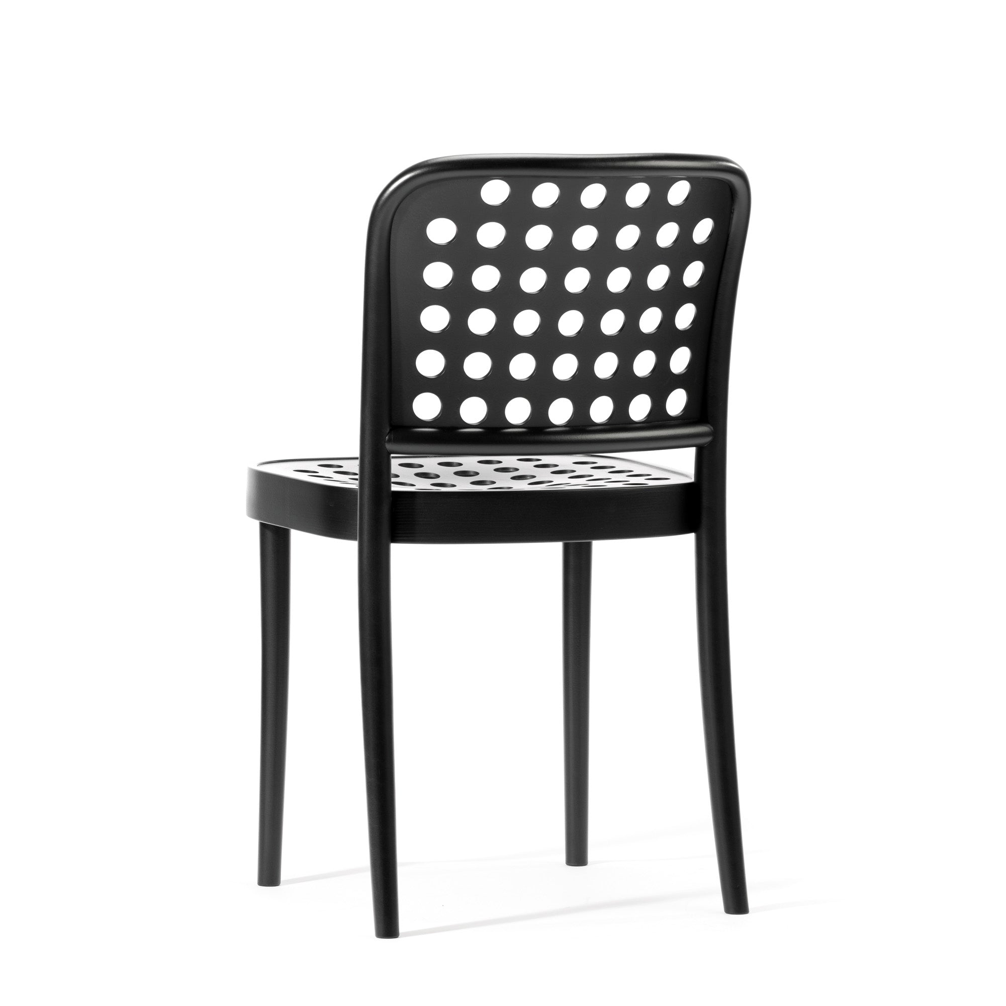 Chair 822 by TON epitomizes Scandinavian minimalism with its modern black design, featuring a circular cut-out pattern on the backrest and seat. Crafted using TONDesigners manual wood-bending technology, it stands on four slender legs against a plain white background.