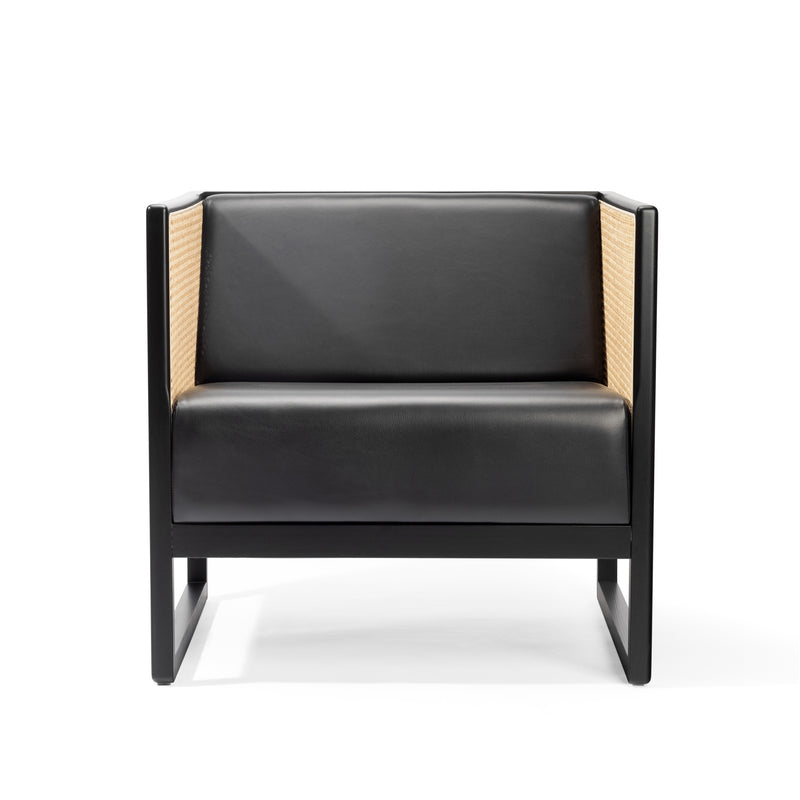 The Armchair Casablanca by TON features a sleek, modern design with black leather and a dark wood frame. Its back and sides showcase light woven material akin to cane weave. The chairs clean lines perfectly enhance its minimalist aesthetic on a white background.