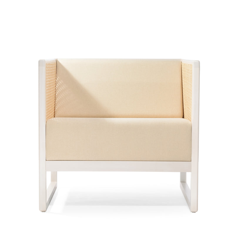 The Armchair Casablanca by TON features a minimalist design with a light beige cushioned seat and high backrest, complemented by sleek white wooden armrests and cane weave detailing on the sides.
