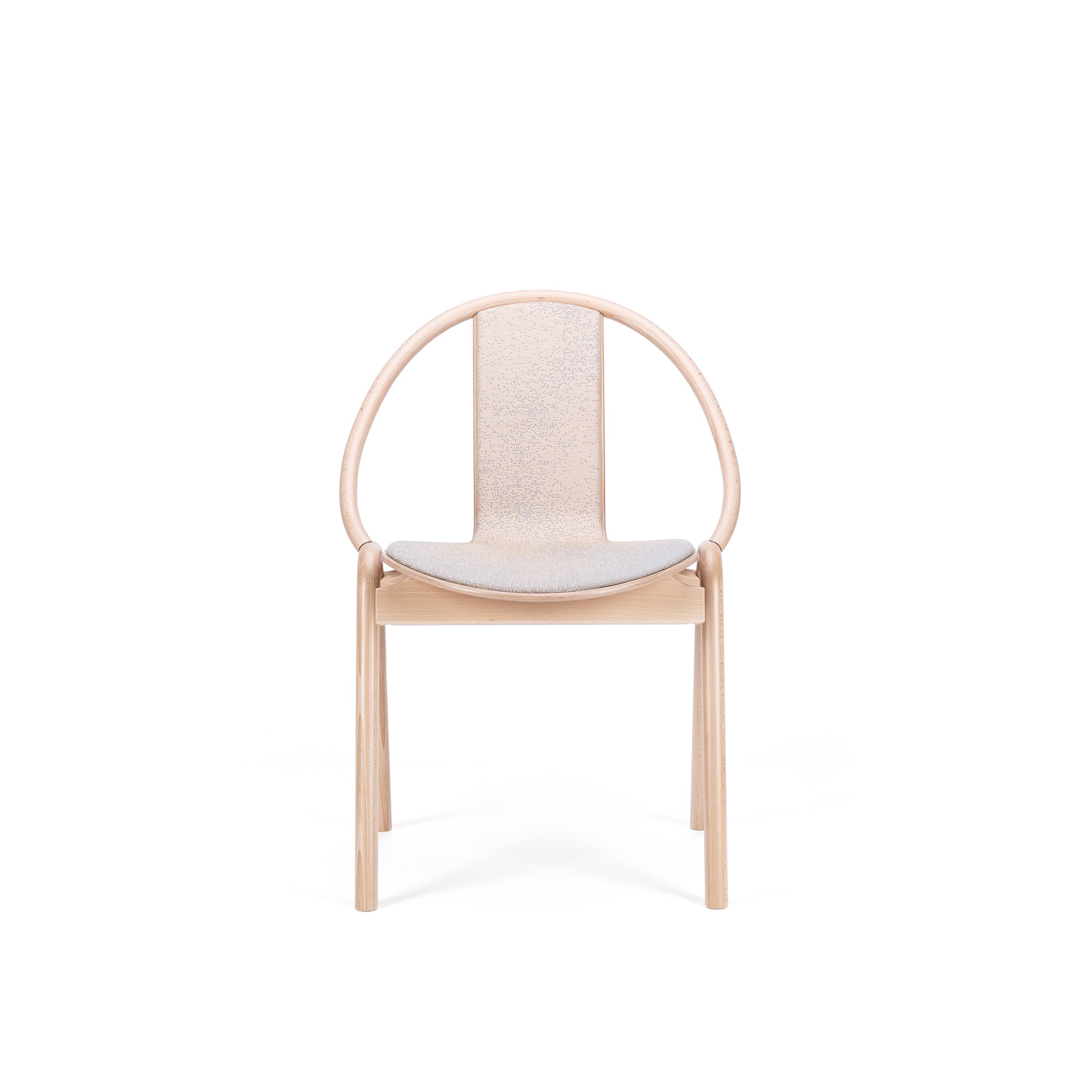 The Chair Again Upholstered by TON is a minimalist design crafted from solid beech wood, featuring a smooth circular backrest and cushioned seat. Its modern and elegant structure boasts light-colored wood, enhancing its sophisticated look against white backgrounds.