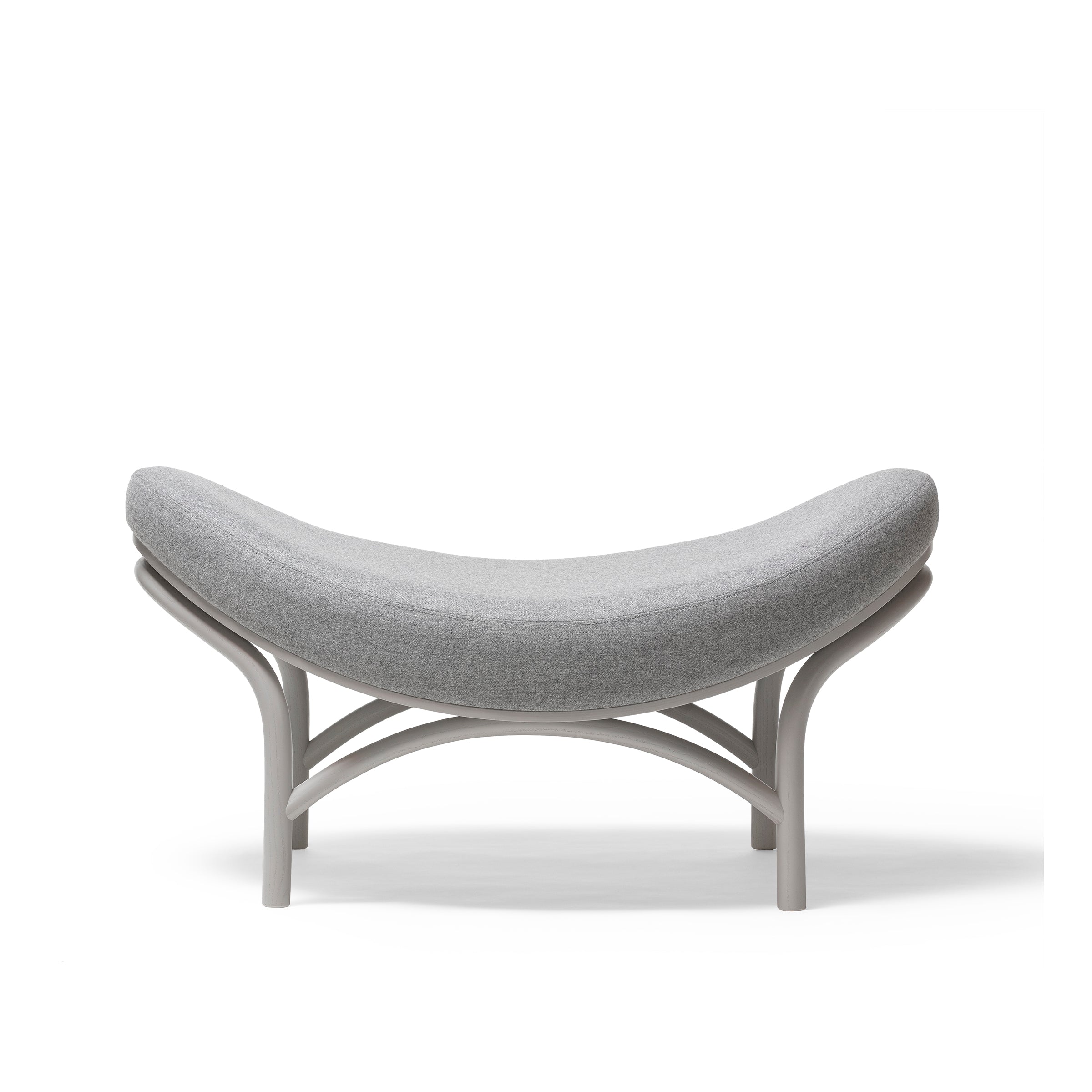 The Ottoman Chips by TON is a modern, curved bench with manually-bent wood, featuring a light grey cushioned seat and smooth arched legs on a plain white background.