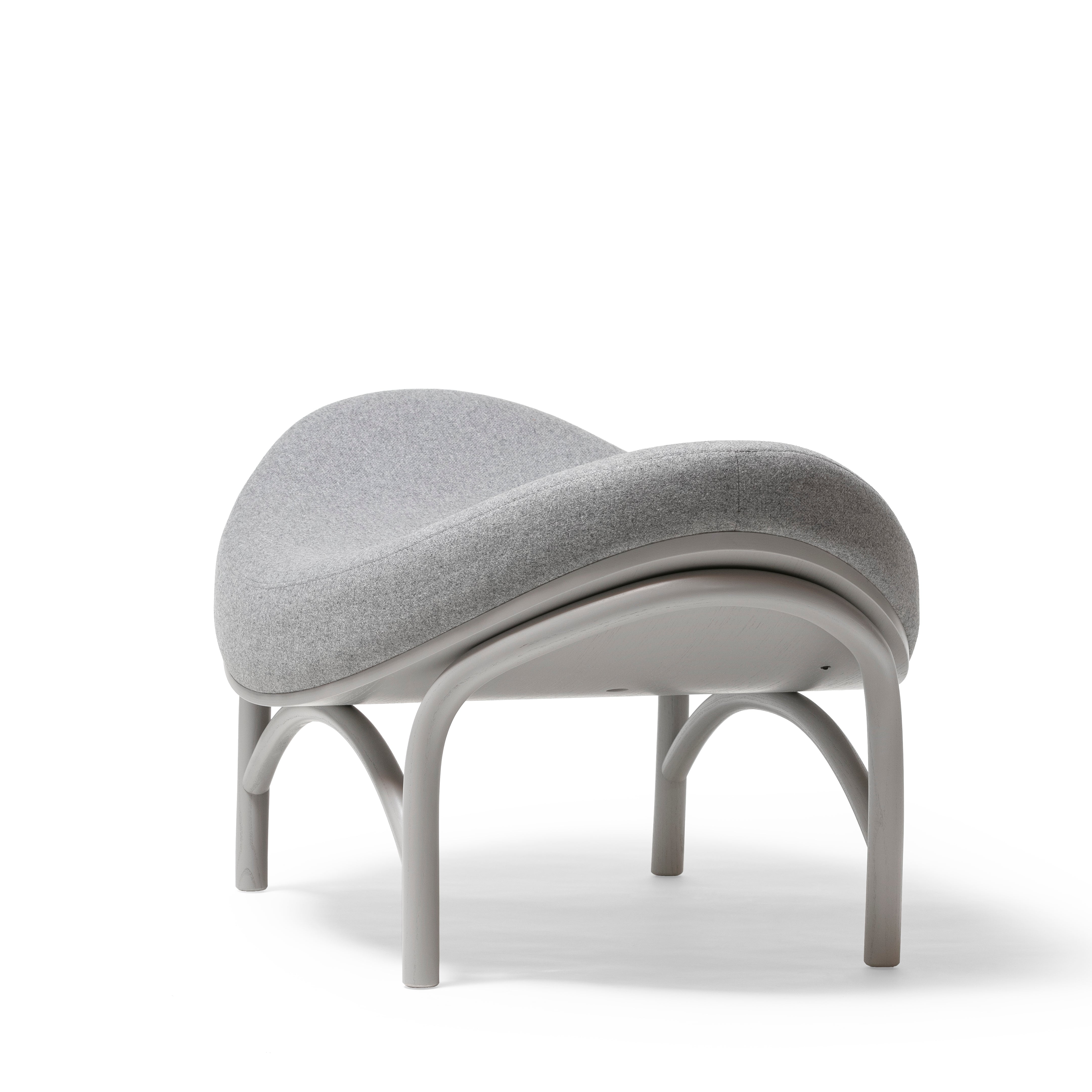 Introducing the Ottoman Chips by TON: a modern, sculptural piece with a gray, curved seat and backrest, supported by a light gray arched frame made from manually-bent wood. Its sleek design with comfortable upholstery offers a contemporary feel against the white background.