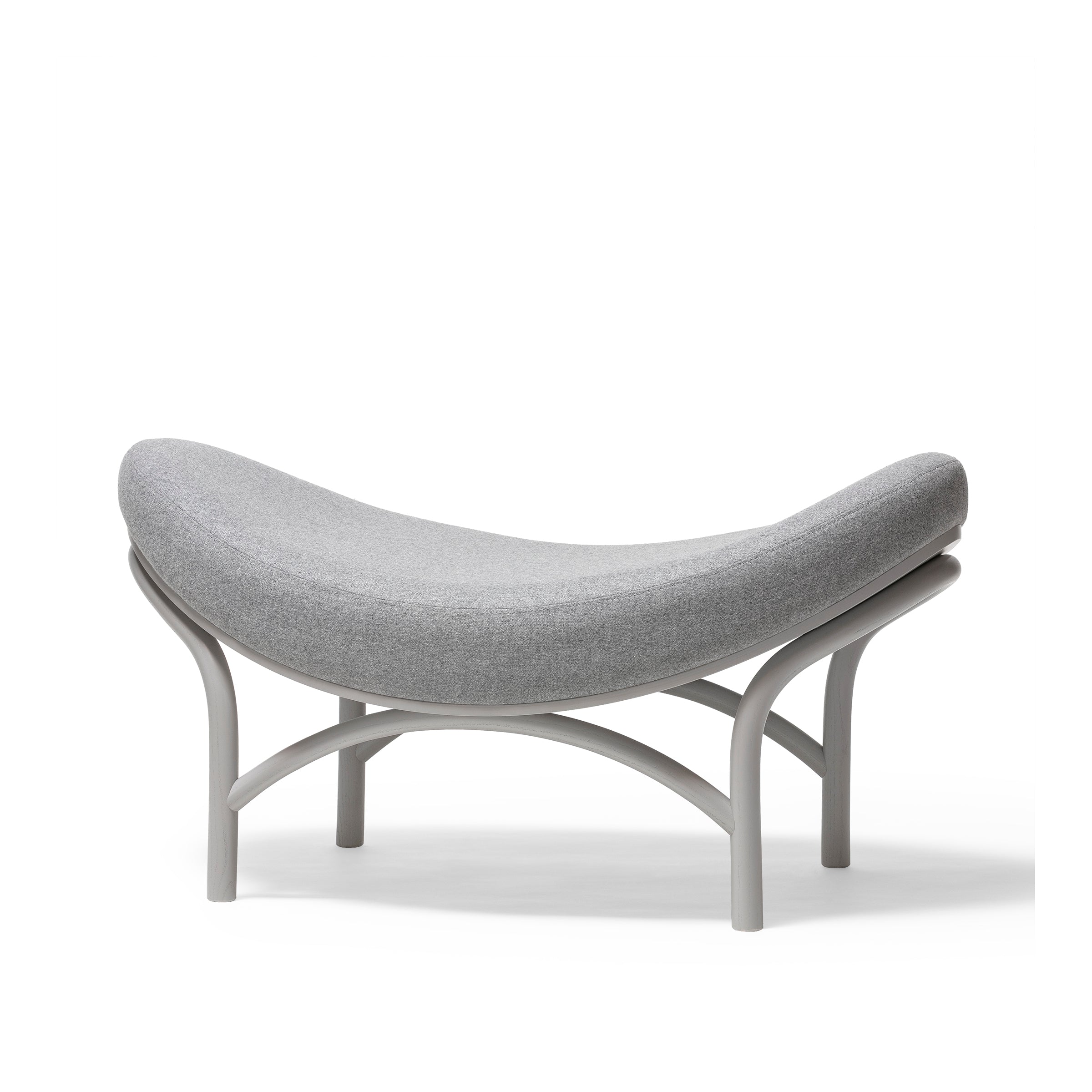 The Ottoman Chips from TON features a stylish gray cushion atop a minimalist metal frame. Its modern design blends comfort and elegance, with edges arching upwards like manually-bent wood artistry.