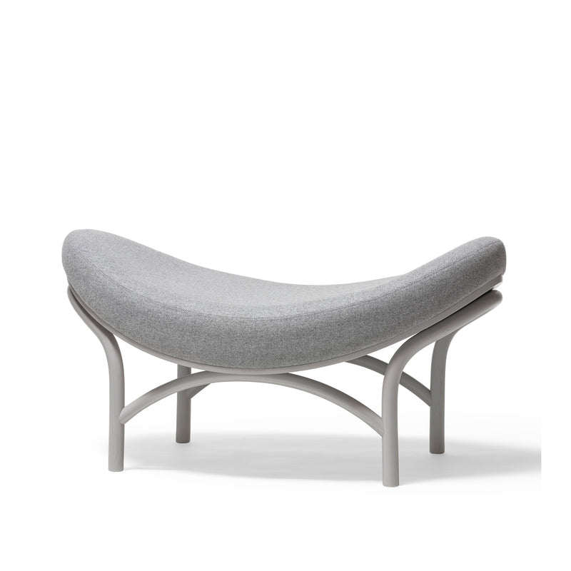 The Ottoman Chips from TON features a stylish gray cushion atop a minimalist metal frame. Its modern design blends comfort and elegance, with edges arching upwards like manually-bent wood artistry.