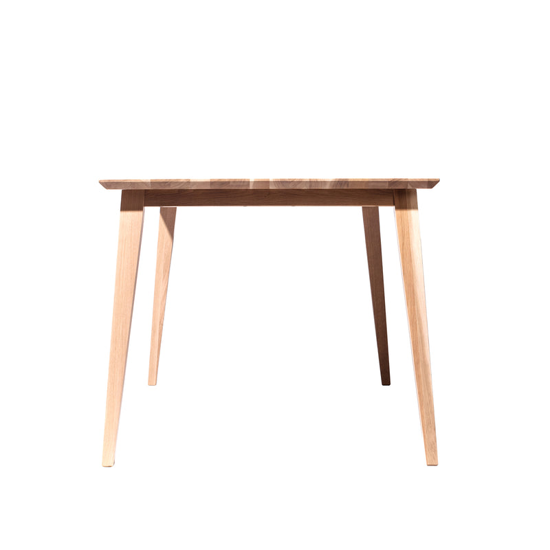 The Jylland Table by TON features a simple, modern Scandinavian design with a flat rectangular top and four angled legs. Its solid wood craftsmanship is highlighted by visible grain, all set against a crisp white background.