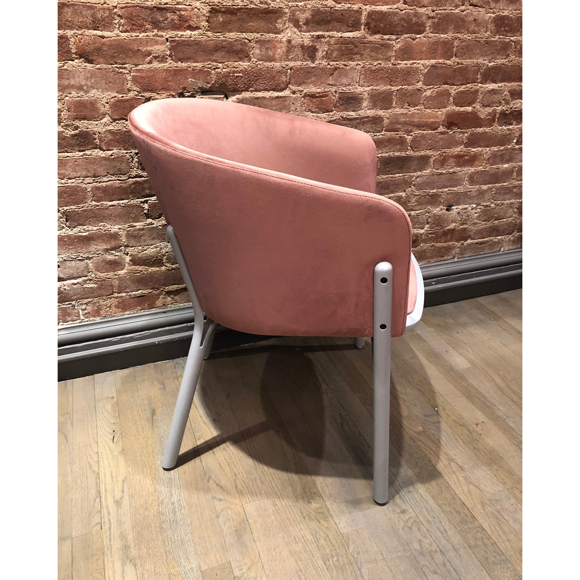 The Armchair Split - Sale by TON features a velvet seat with a curved backrest and sleek metal legs, beautifully complementing the rustic brick wall and wooden floor for a cozy yet modern vibe through its ergonomic design.