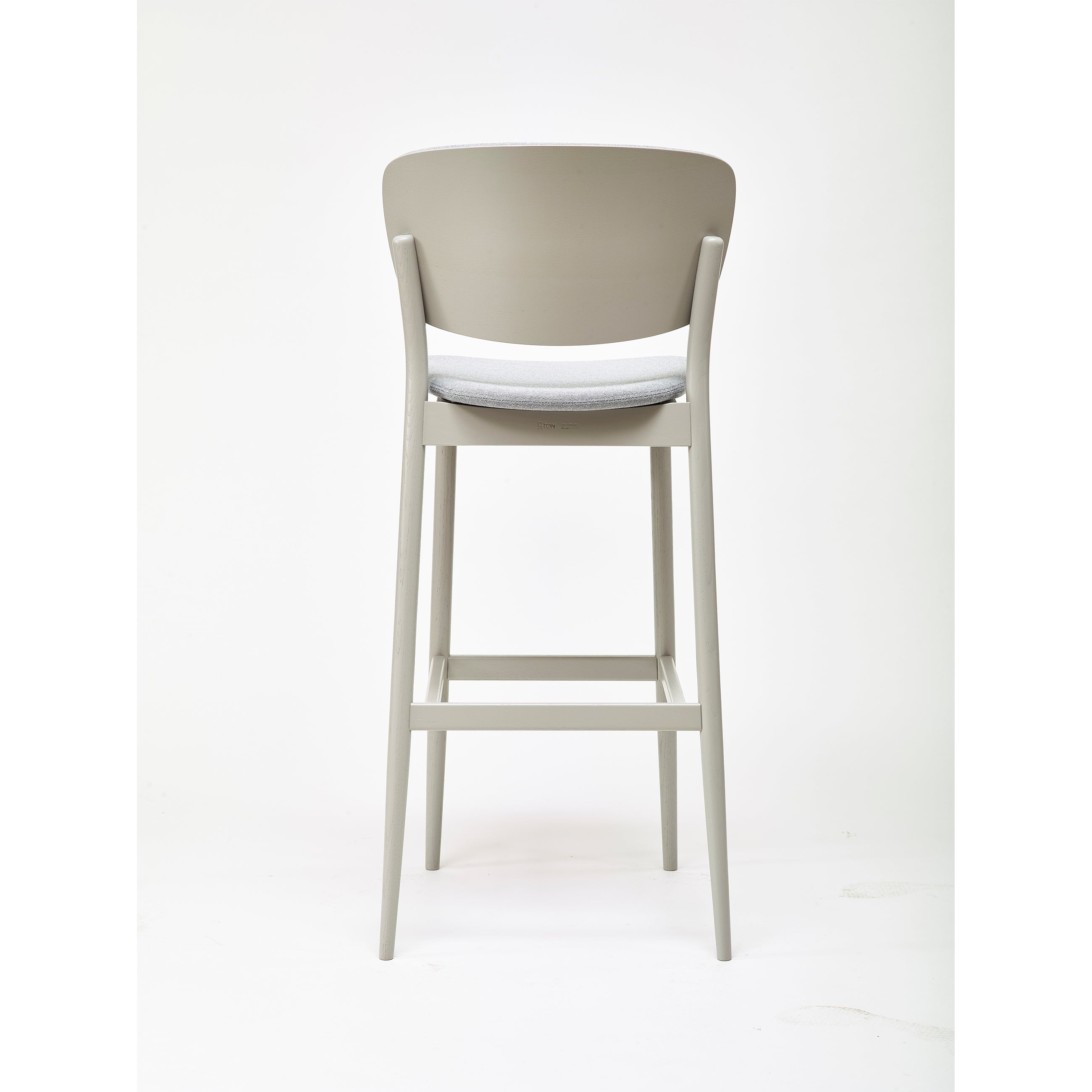 The Barstool Valencia, crafted by Yonoh for TON, showcases a minimalist design with a light gray finish, curved backrest, and cushioned seat. Set against a white background, this high barstool exudes sleek elegance from every perspective.