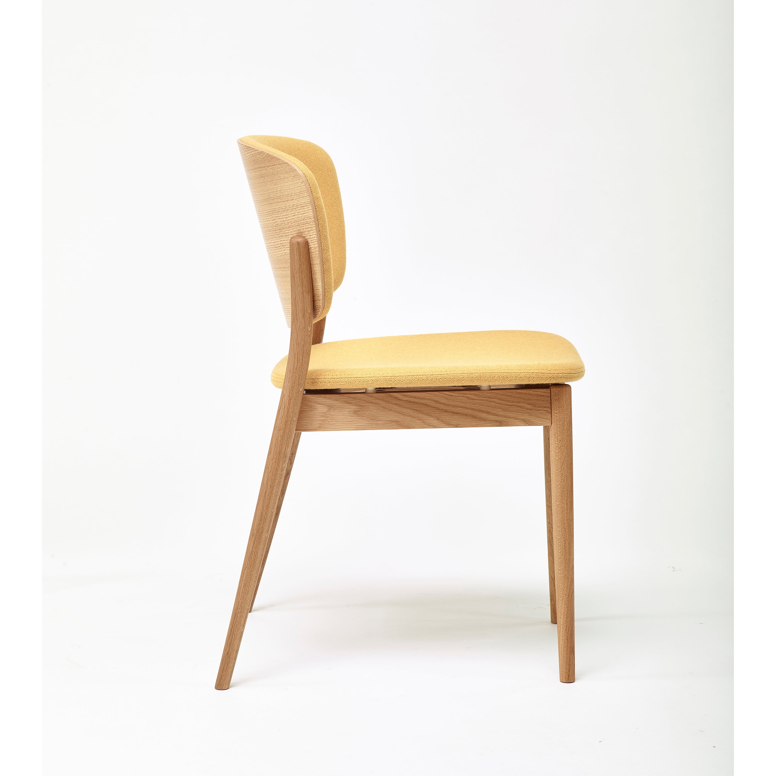 A side view of the TON Chair Valencia Upholstered - Sale showcases its light yellow cushions and ergonomic design. Made from solid wood with a minimalistic look, it features slightly angled legs against a plain white background.