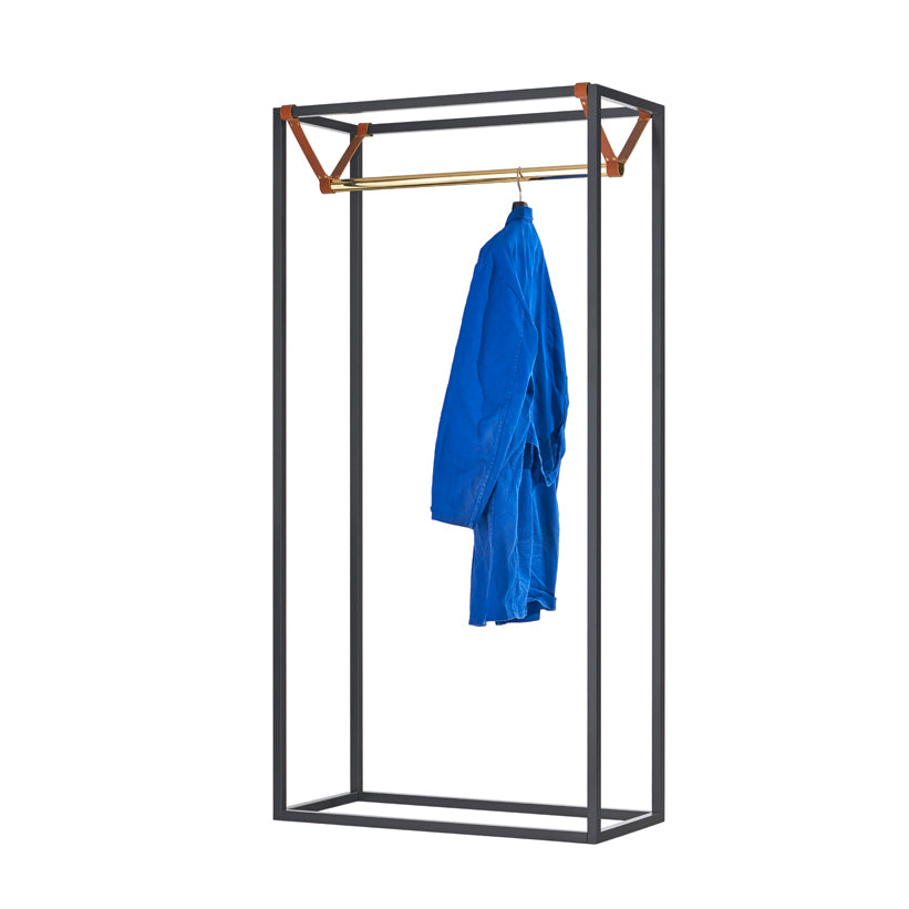 The LESS MESS Coat Stand by Victor Foxtrot features a sleek, minimalist black powder-coated steel frame with a polished brass rod. Brown vegetable-tanned leather accents at the corners add an elegant, industrial touch, perfectly showcasing a single blue garment.