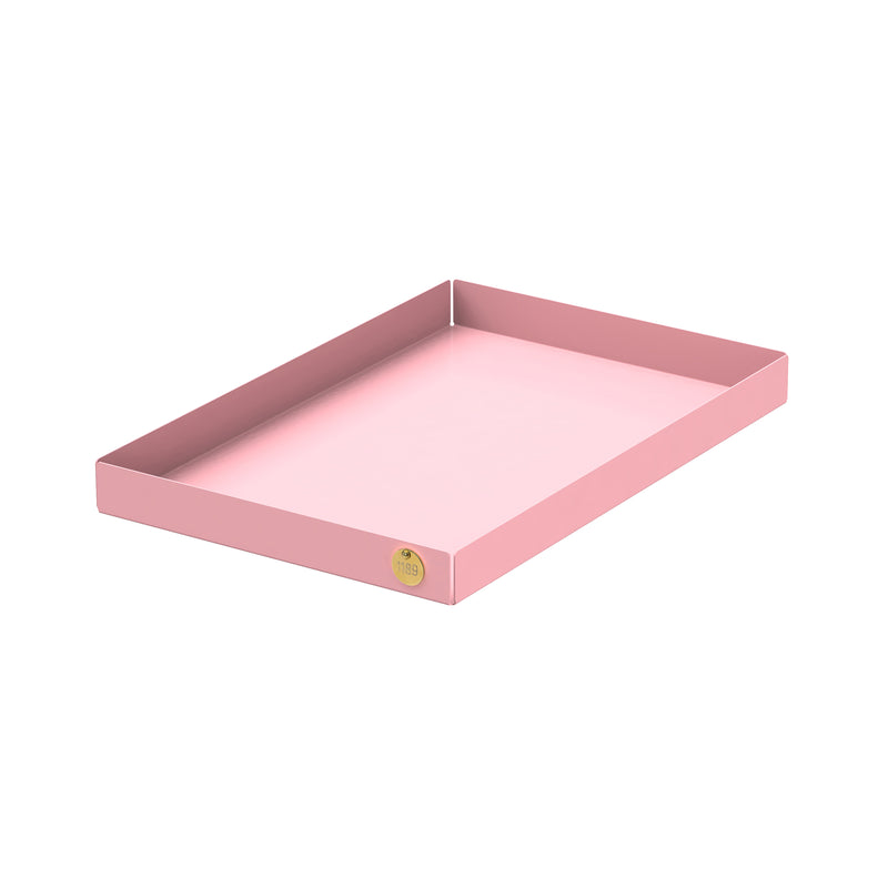 The POI Tray L by Victor Foxtrot is a pink, powder-coated steel tray with raised edges for durability. A small round sticker adorns one corner when viewed at an angle, showcasing its minimalist elegance against a plain white background.