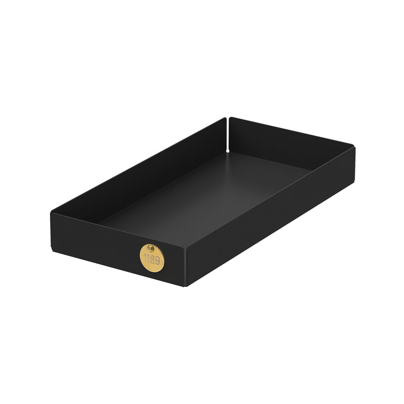 The POI Tray M by Victor Foxtrot is a black, rectangular, open-top tray with raised sides made from powder-coated steel. It includes a gold-colored circular label marked 1189 in one corner. With its simple design, it serves as an ideal organization solution or gift for design lovers.