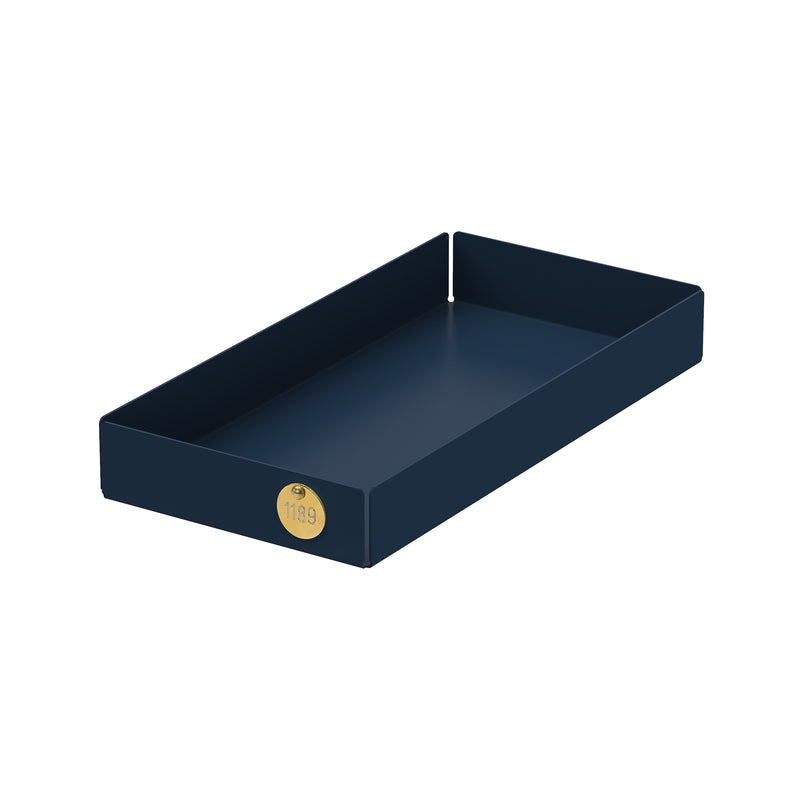 The POI Tray M by Victor Foxtrot, made from powder-coated steel, showcases a dark blue rectangular body and a brass emblem with 1199 on one corner. With its modern minimalist design and raised edges, its ideal for design lovers in search of elegant storage solutions.