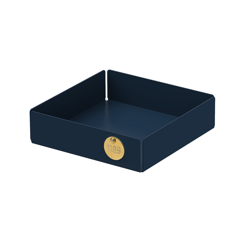 The POI Tray S by Victor Foxtrot is a square, dark blue tray made of powder-coated steel. It has high edges, a small round gold sticker on one side, and a simple modern design that appeals to design lovers, making it ideal for organizing or displaying items.