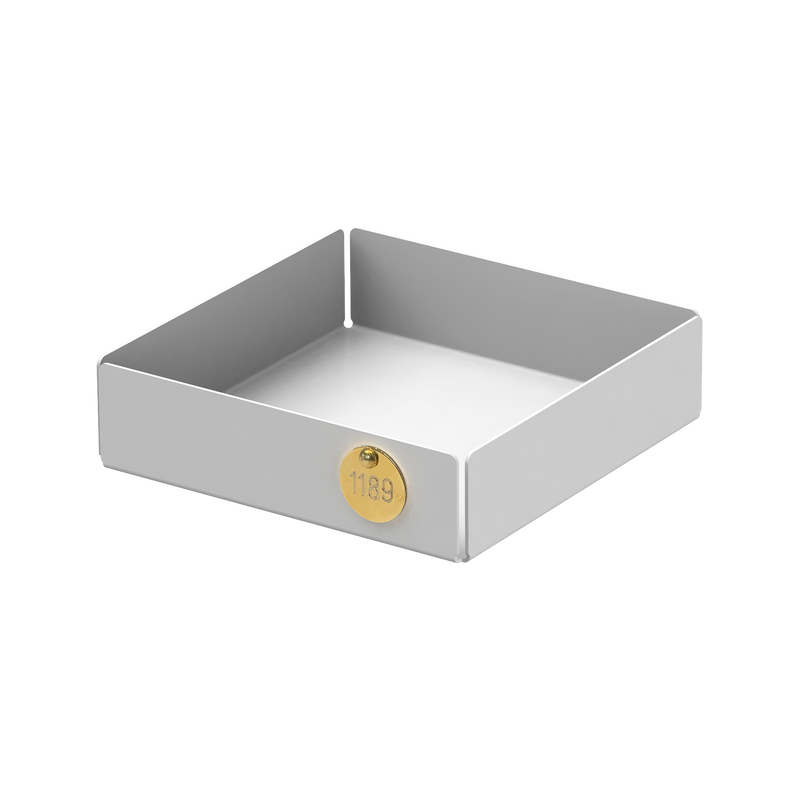 The POI Tray S by Victor Foxtrot is a square, gray powder-coated steel container with short walls and a round, gold-colored label with the number 1189. Ideal for minimalist design lovers, it sits empty on a plain background.