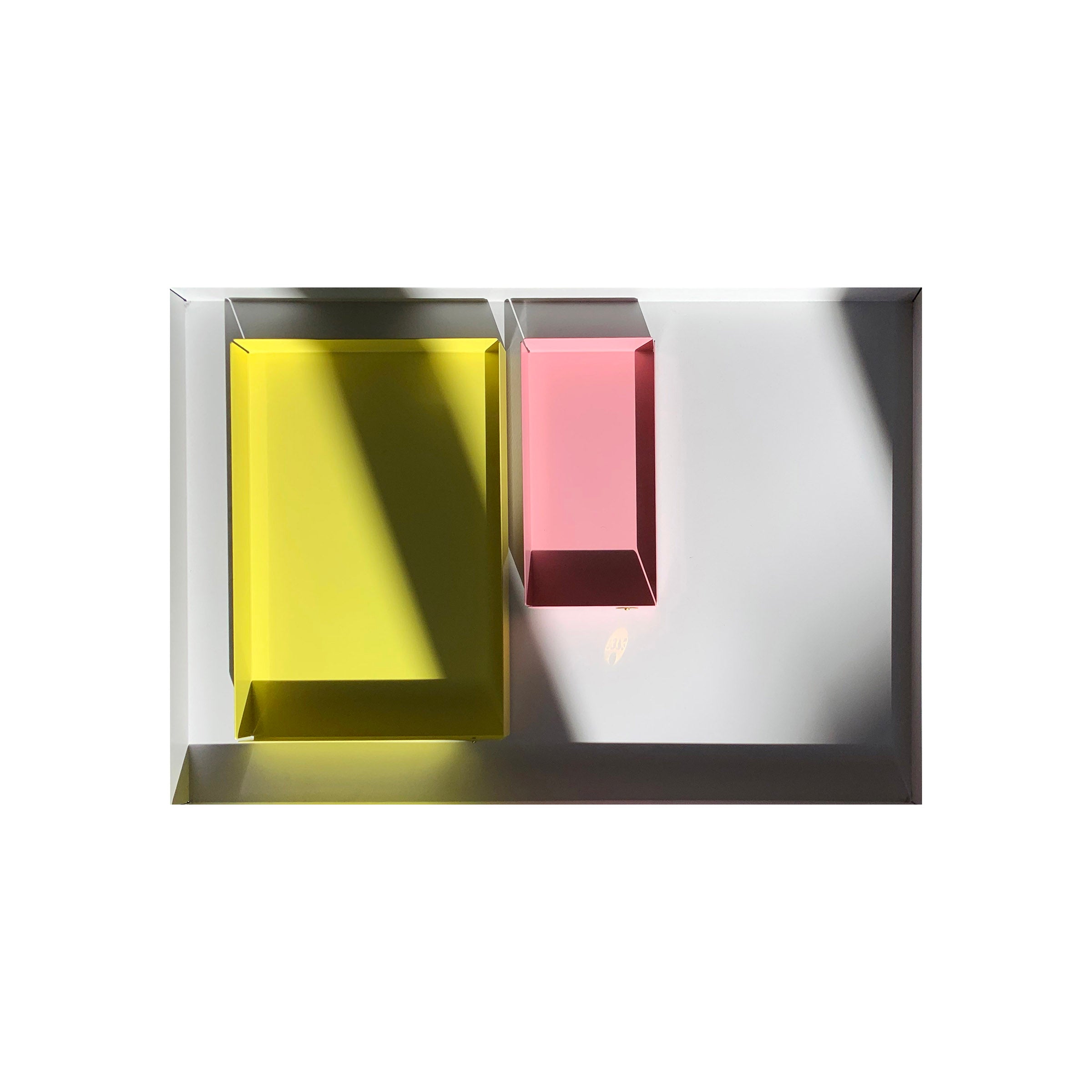 The POI Tray L by Victor Foxtrot showcases a minimalist design with two transparent blocks, one yellow and one red, on a powder-coated steel surface. The blocks cast distinct shadows, creating an abstract geometric composition with striking contrasts.