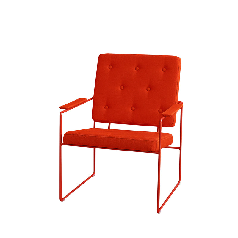 The SWELL TIME Lounge Chair by Victor Foxtrot is a modern designer chair with a bright orange upholstered seat and button-tufted backrest. It features a minimalist design with sleek steel frame armrests and base, set against a plain white background.