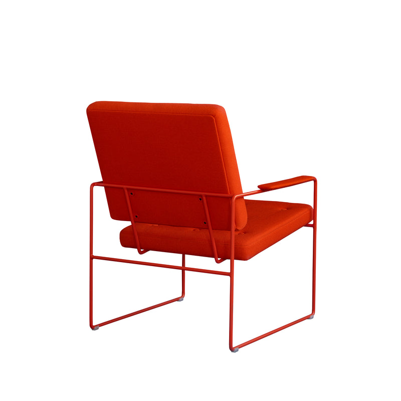 The SWELL TIME Lounge Chair by Victor Foxtrot is a modern designer piece featuring British upholstery with an orange cushioned backrest and seat on a slim, matching painted steel frame. Its angled design showcases the sleek back and sides.