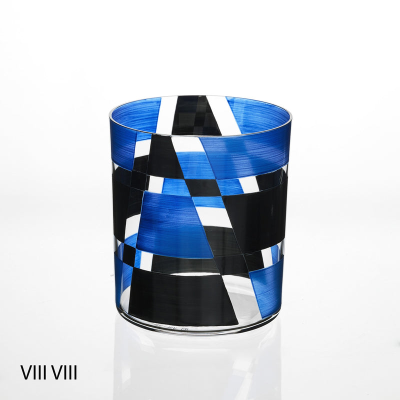 The Neo Light VIII Enamel Collection glass tumbler by Lobmeyr, designed by Martino Gamper, features a modern geometric flair with blue, black, and white diagonal stripes. The abstract design includes subtle VIII VIII text in the bottom left corner.