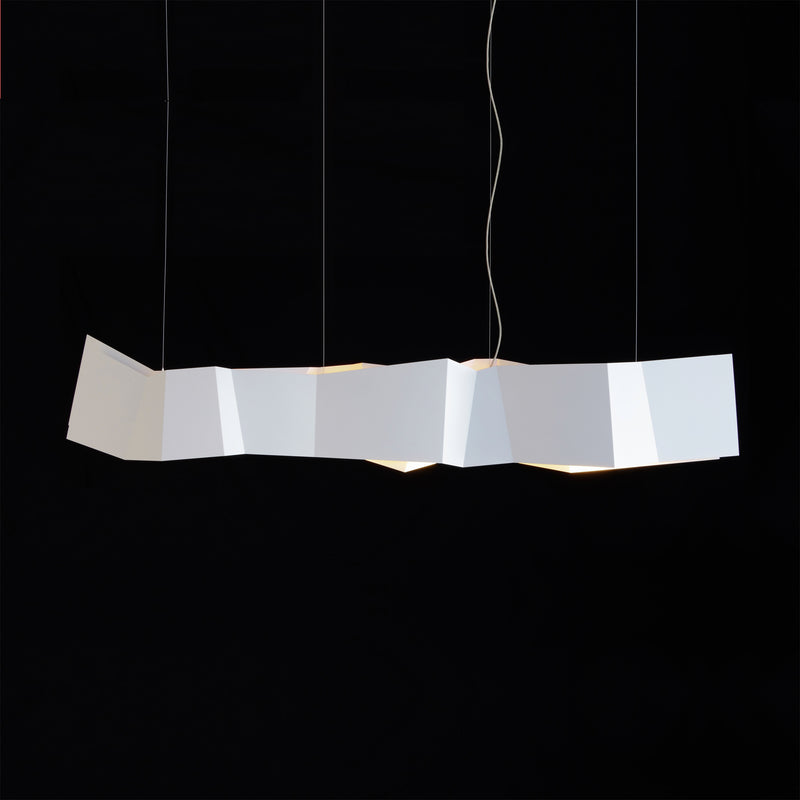 The ZIG ZAG Pendant Lamp by Victor Foxtrot hangs against a black backdrop, showcasing its origami-inspired design with folded geometric shapes. Ideal for restaurants, it suspends by thin wires and emits a soft glow from within the folds.