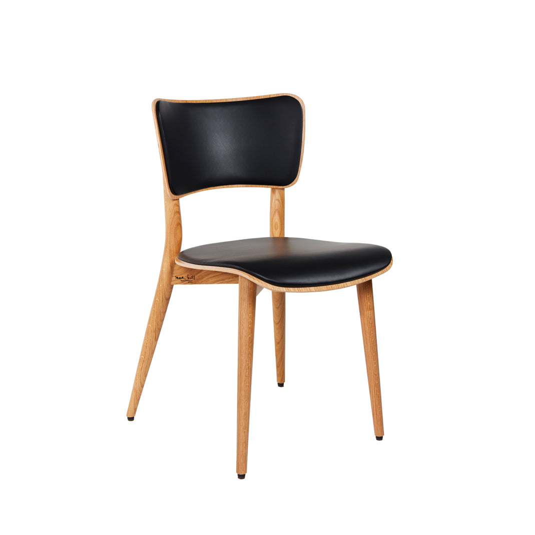 The Kreuzzargenstuhl Chair by WB Form is a modern cross-framed design with a wooden structure and four legs, featuring a black cushioned seat and backrest. It harmonizes contemporary aesthetics with natural elements reminiscent of Max Bills design.
