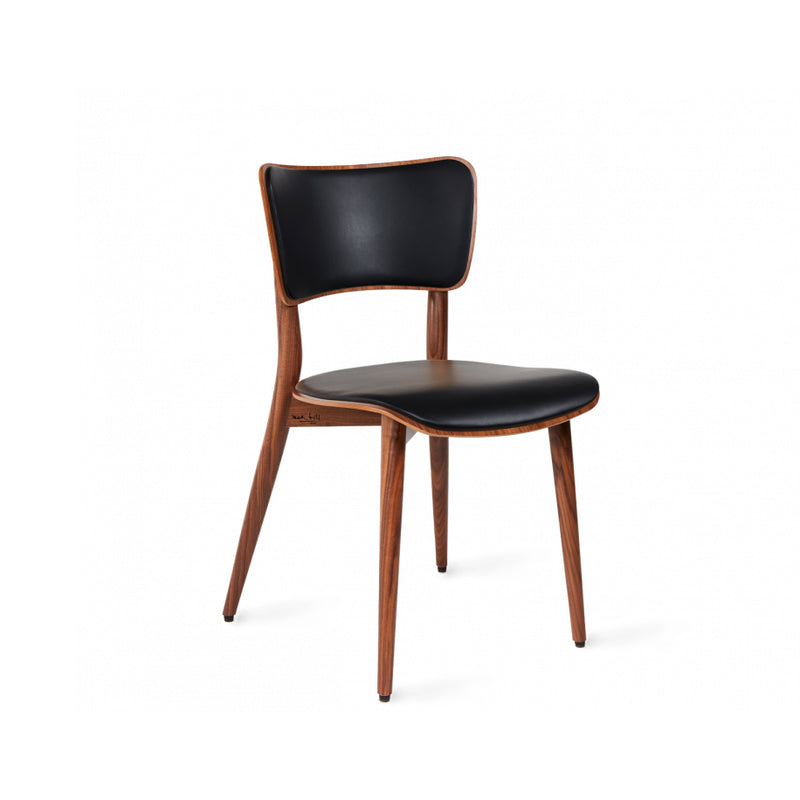 The Kreuzzargenstuhl Chair by WB Form is a wooden cross-framed chair with a sleek, minimalist design, featuring a curved backrest and four angled legs. It offers multiple upholstery options, including black leather, for a modern aesthetic.
