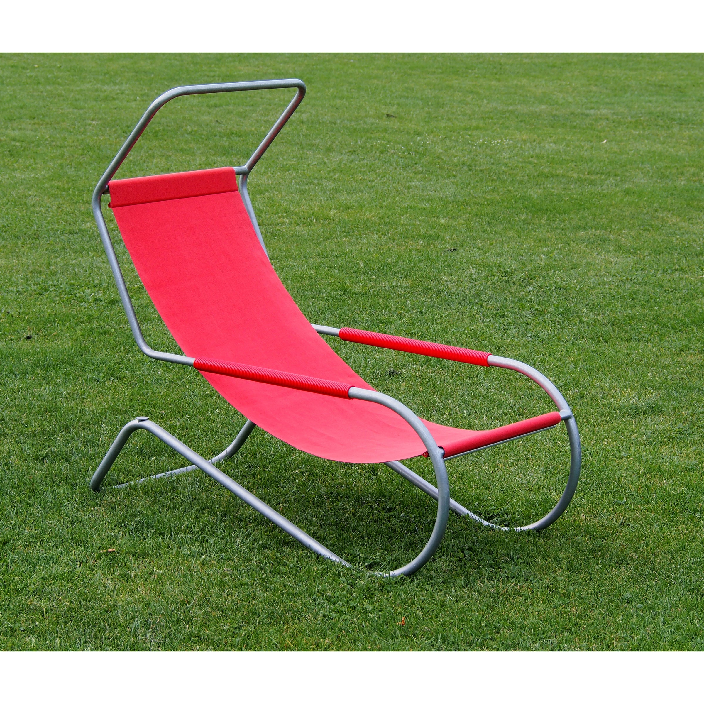 The Lido Lounger by WB Form is a modern red fabric cantilever chair on a vibrant green lawn. It features a sleek metal frame and minimalist design with curved metal legs and a rectangular headrest.
