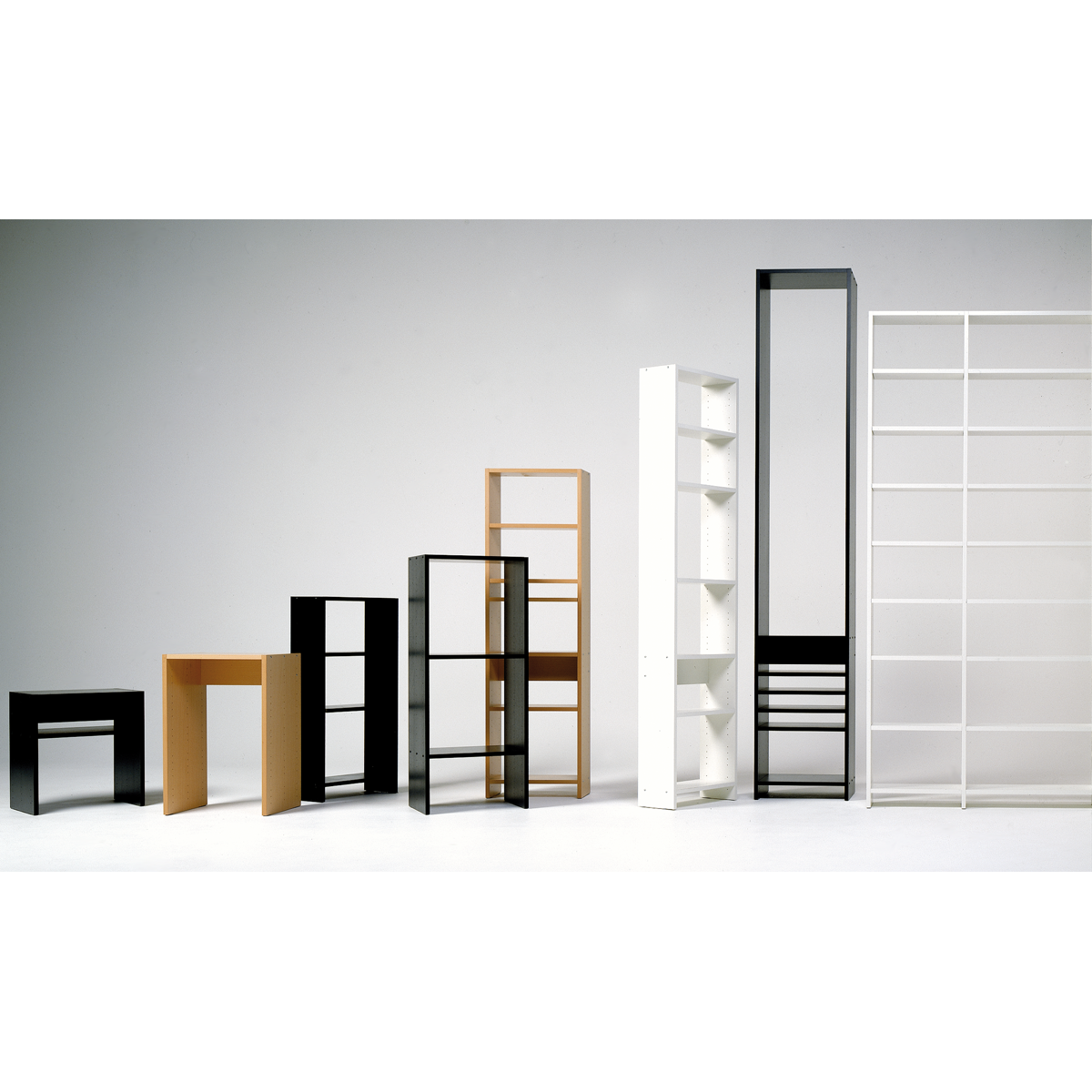 Displayed against a white background, the UPW Shelf by WB Form offers minimalist bookshelf units crafted from sustainable materials in black, white, and wood tones. Some shelves feature closed back panels while others have an open shelving system.