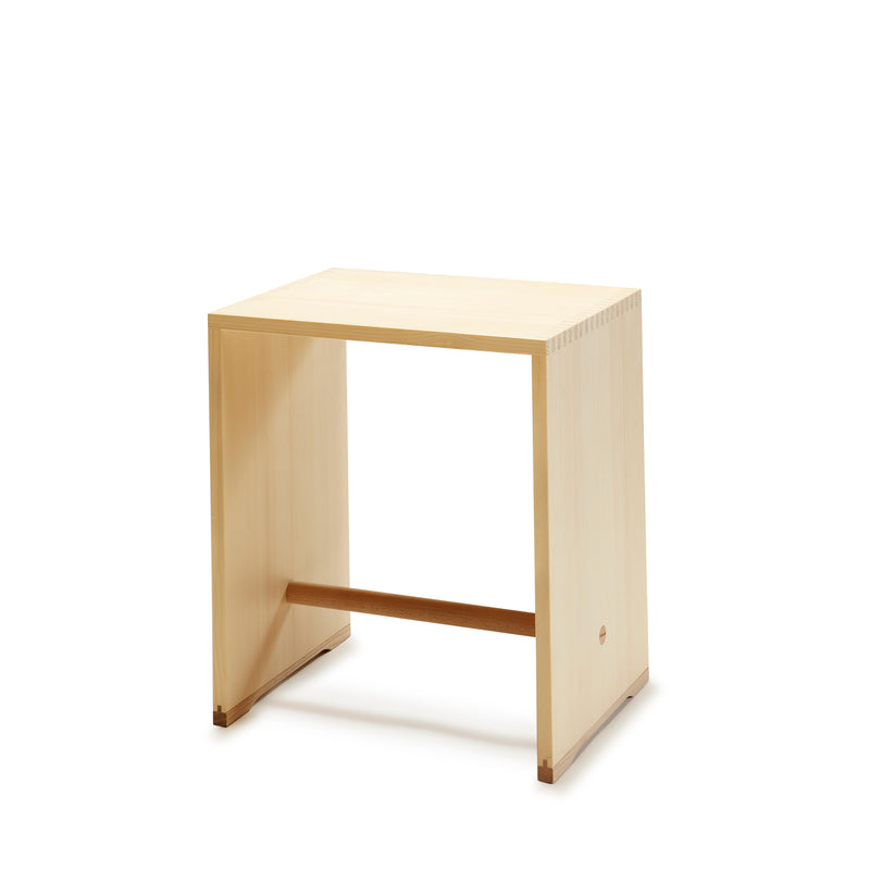 The Ulmer Stool by WB Form is a minimalist and versatile piece with flat surfaces and clean lines, featuring a rectangular seat, sides, and a horizontal support bar near the base. Its light finish is reminiscent of the Max Bill Ulm Stool and rests elegantly on a white background.