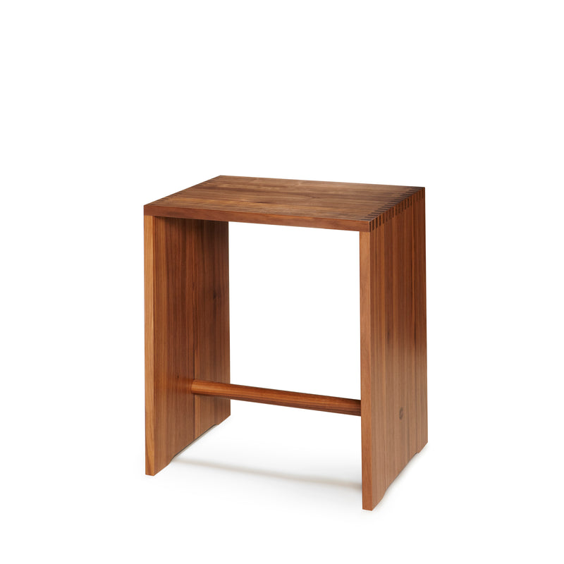 The Ulmer Stool by WB Form features a minimalist design similar to the Max Bill Ulm Stool, with a rectangular top and flat side panels. Its available in nine finishes, including a warm brown with rich wood grain, making it stylish and adaptable for any space.