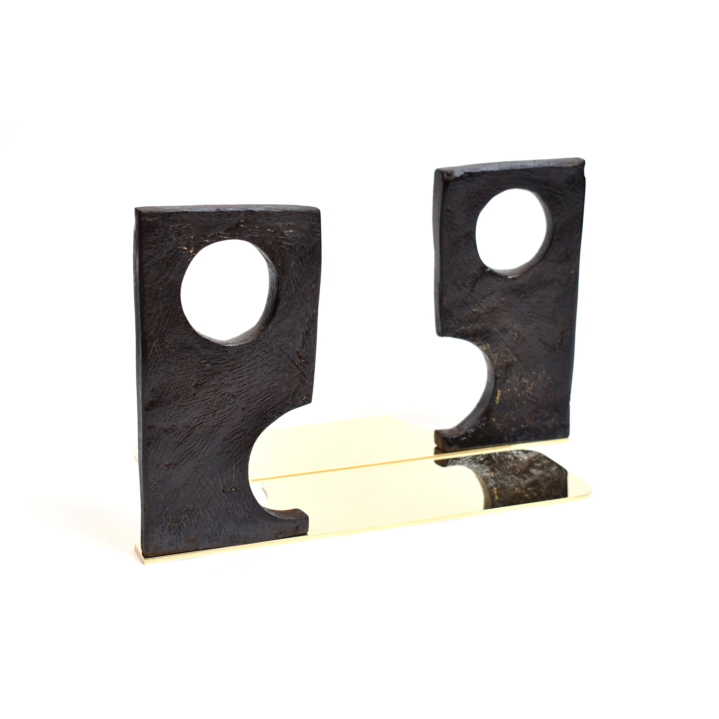 The Pair of Bookends #3785 Urban Legend by Werkstätte Carl Auböck showcases modern black sculpted bookends with circular cutouts on a shiny base, featuring asymmetrical shapes and smooth textures for an artistic look.