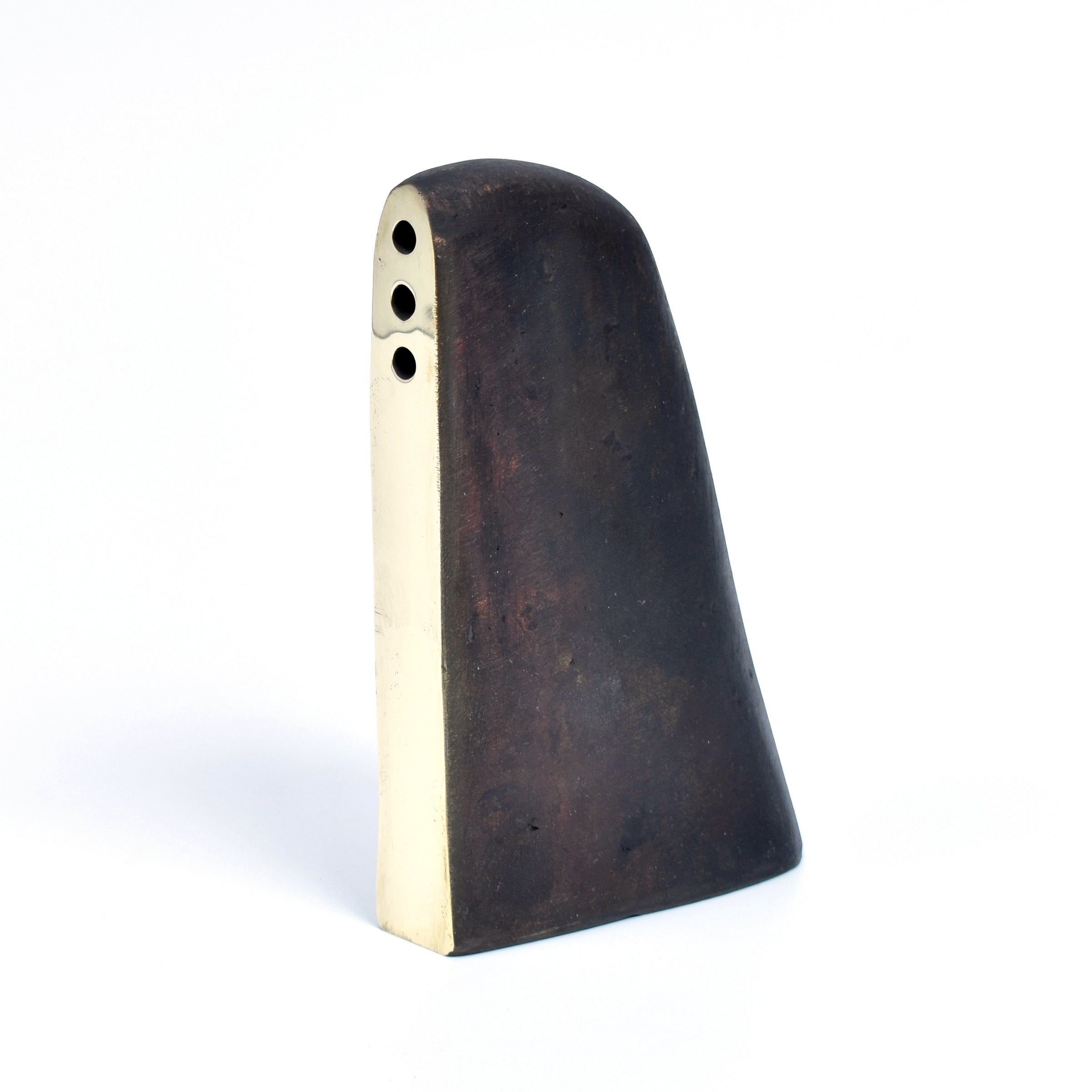 This modern abstract Vase / Bookend Alert #3786 by Werkstätte Carl Auböck showcases a smooth, curved surface with a tapered shape. It features a dark and light contrast, three small circular top holes, and echoes Wiener Bronzen craftsmanship against a plain white background.