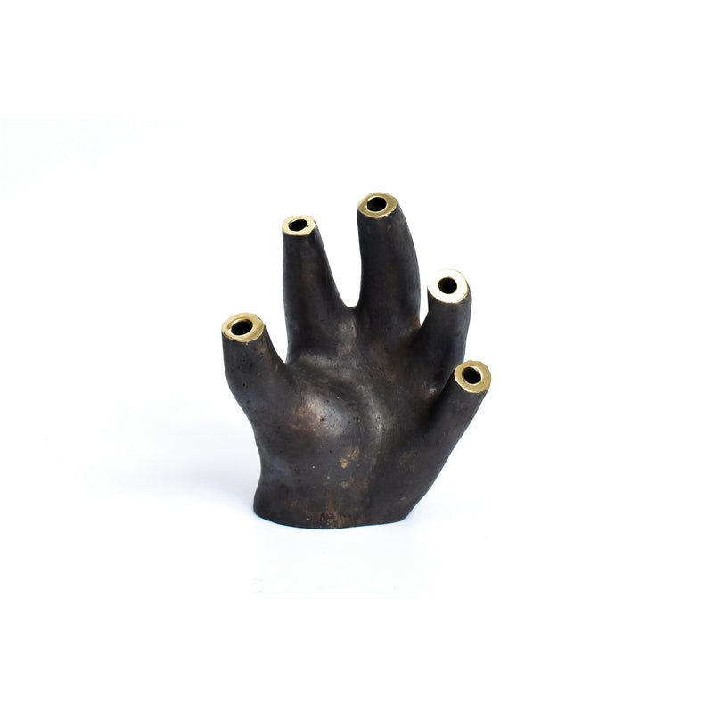 Vase Glove #3788 by Werkstätte Carl Auböck is a dark, sculptural piece resembling an abstract hand with five cylindrical openings. Its textured surface and artistic flair are reminiscent of designs showcased at the Triennale di Milano.