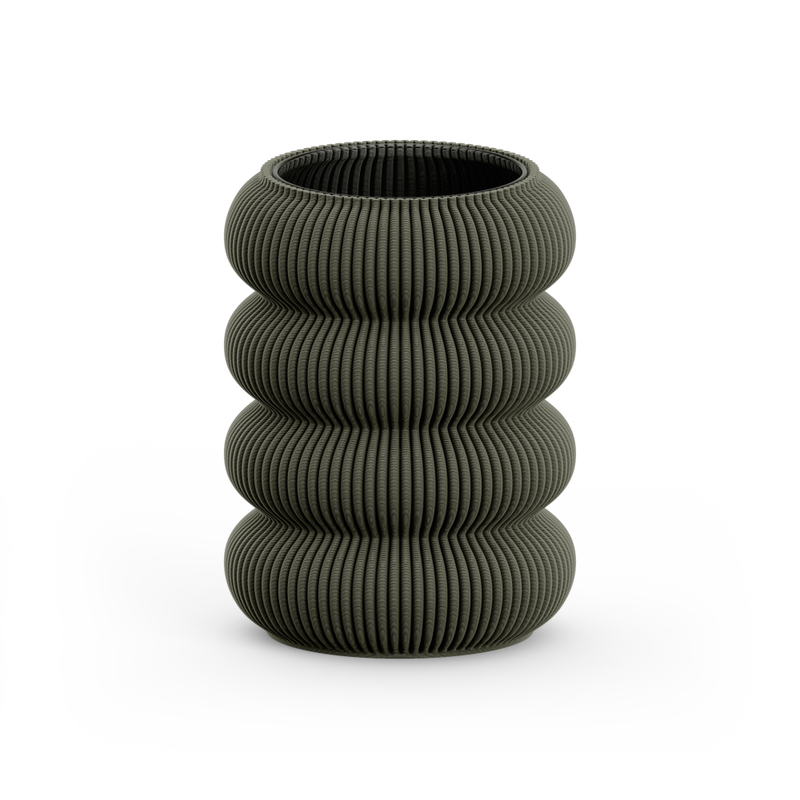 The Sheyn Zayl 130g Vase is a dark gray, vertically ribbed, cylindrical piece resembling architectural pillars. Its stacked, rounded design is crafted through 3D printing into four segmented sections and sits elegantly on a flat white surface.