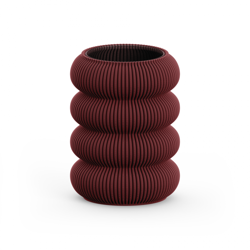 The Zayl 130g Vase by Sheyn features a deep red, ribbed design with four stacked, rounded sections reminiscent of architectural pillars. Crafted from eco-friendly materials, it stands against a white background.