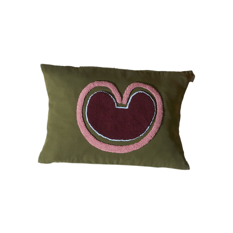The Ames Nido Coraz pillow by Ames is a rectangular olive green cushion featuring an abstract, multicolored embroidered centerpiece with maroon, pink, and white accents—a handmade design inspired by Sebastian Herkner.