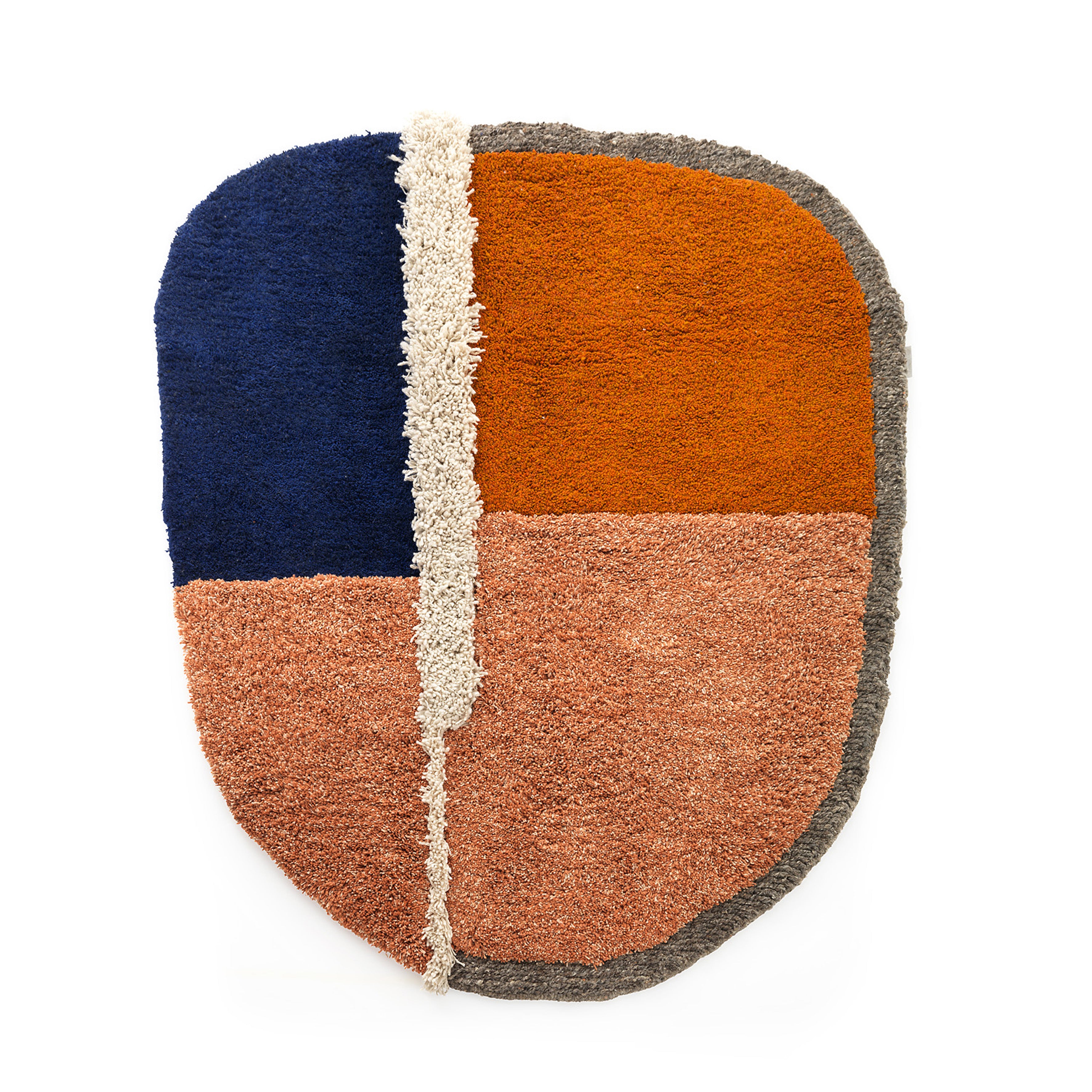 The Ames Nudo Rug features an oval shape with four textured sections: dark blue top left, orange top right, light pink bottom left, and muted grayish pink bottom right. A white vertical strip in the center highlights its exquisite Colombian arts and crafts design.
