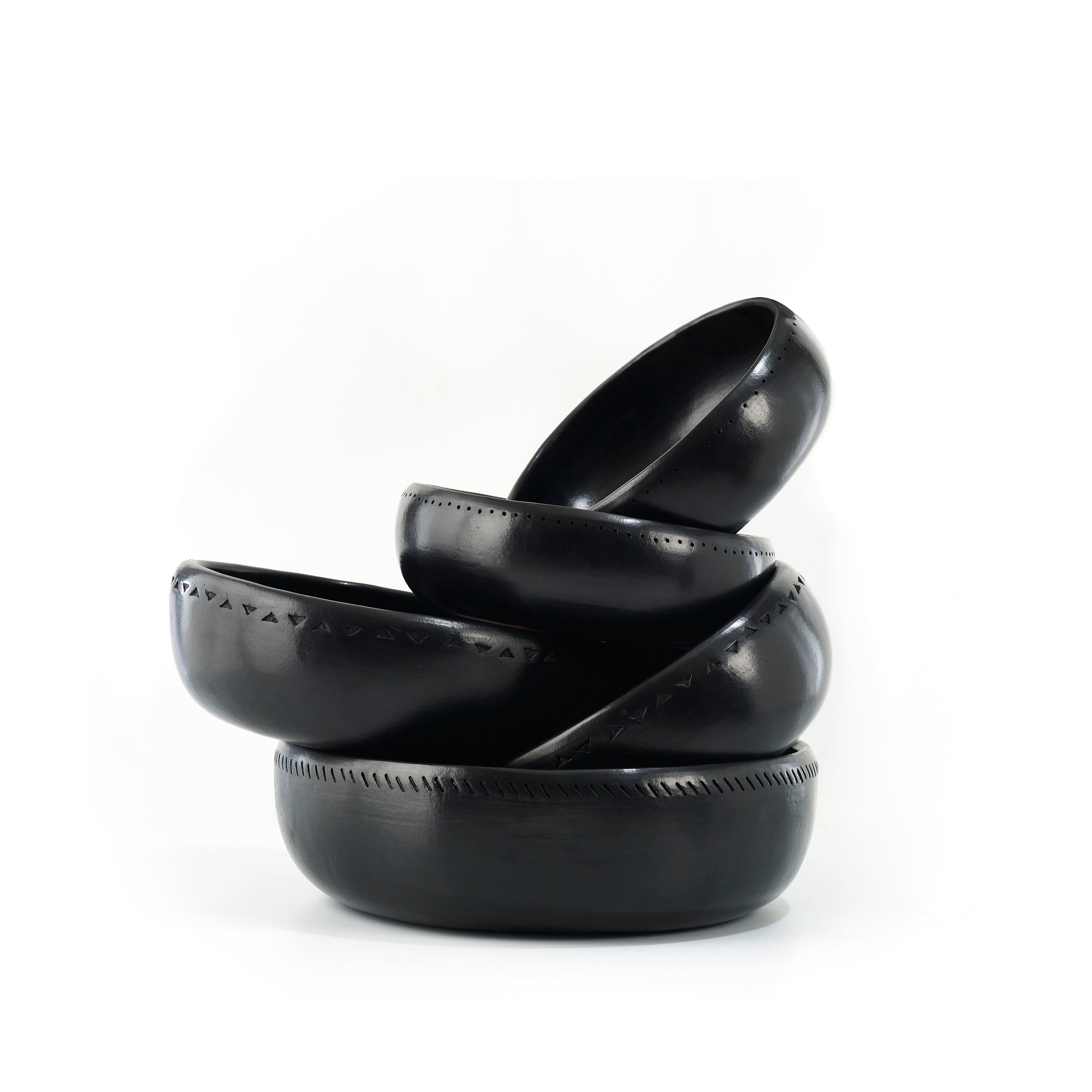 The Barro Bowl from Ames features four stacked black ceramic bowls with embossed geometric patterns, beautifully showcasing traditional pottery against a white background.
