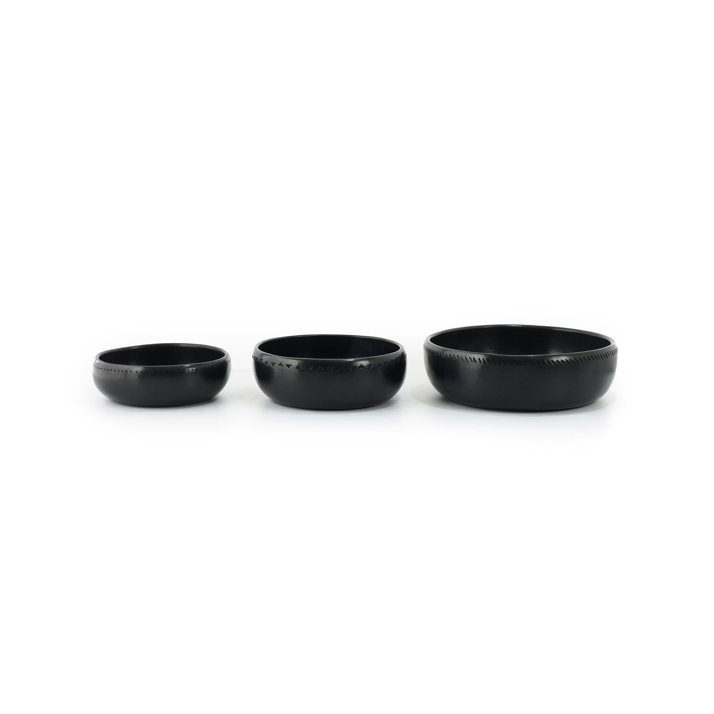 Three handcrafted Ames Barro Bowls, each slightly larger than the last, are lined up. They feature subtle decorative edge patterns reflecting traditional pottery techniques against a plain white background.