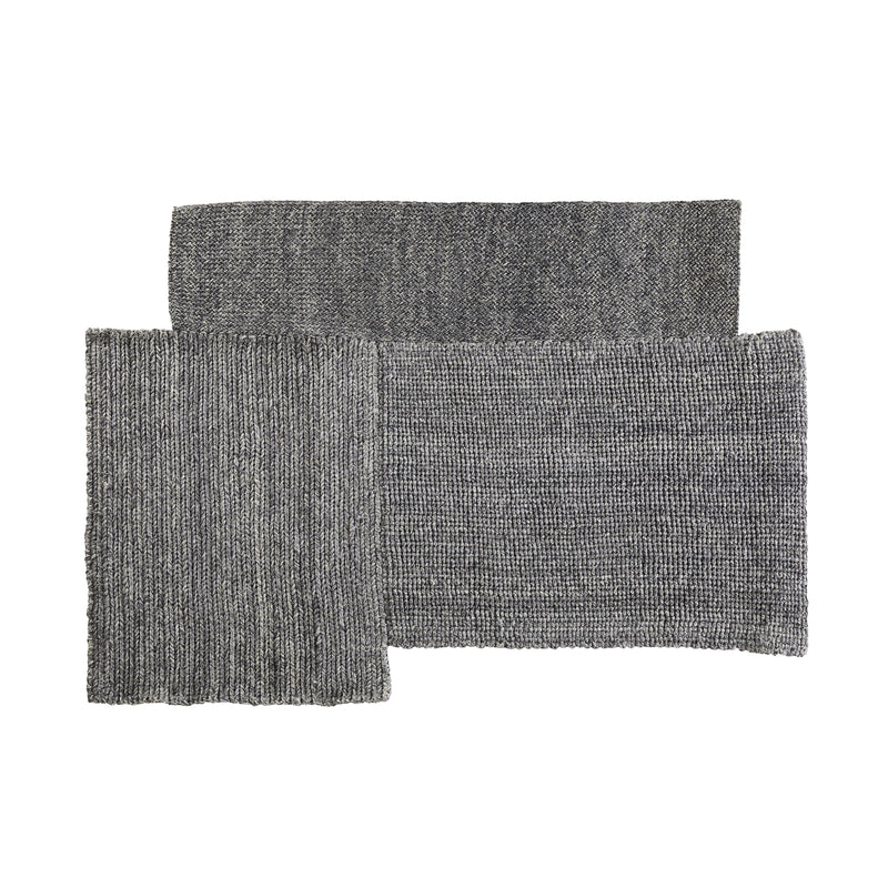 Three overlapping sections of the gray Cabuya Rug by Ames lie flat, showcasing a textured, ribbed design with slight shade variations that exude coziness, reminiscent of Sebastian Herkners natural material designs using exquisite fique plant fiber.