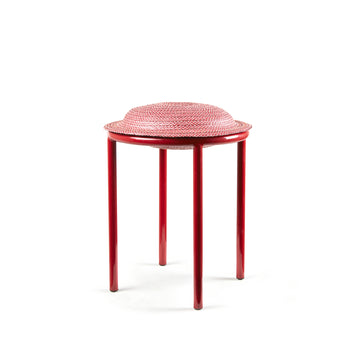 The Ames Cana Stool has a textured, circular seat on three round legs. Its vibrant colors contrast with a plain white background, adding style to any modern space.