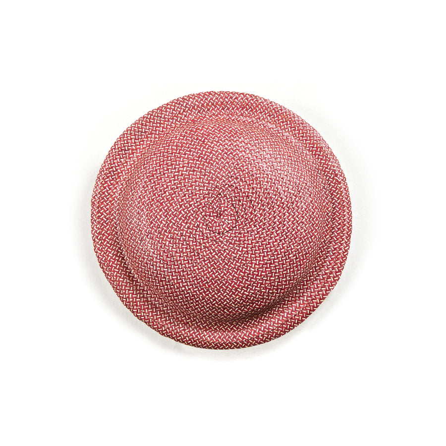 On a plain white background, the Cana Stool by Ames features vibrant colors similar to a round, textured pink woven straw hat with a flat brim and slightly elevated crown.