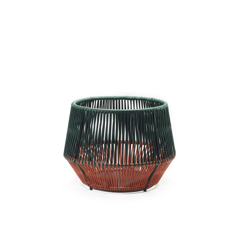 The Caribe Chic Basket 2 by Ames is a round, open-weave basket with a geometric design crafted using the mamposino braiding technique. Made from recycled plastic strings, its top half is dark green and the bottom is rust-colored, giving it a modern look against a white background.