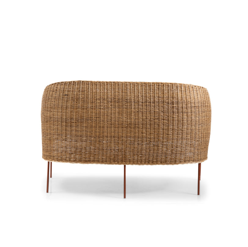 The back view of the Caribe Natural Sofa, designed by Ames, reveals an oval shape and curved design reminiscent of Caribbean chairs. It boasts thin metal legs and a natural wicker finish that highlights Colombian craftsmanship for a minimalist and stylish look.