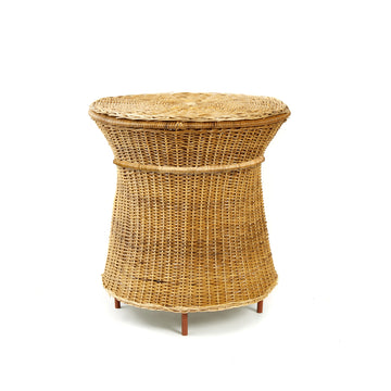 The Caribe Natural High Side Table by Ames features a round, flat top and flared sides crafted from woven wicker. Supported by short wooden legs, its natural texture and color evoke a rustic feel, highlighting the essence of Colombian craftsmanship.