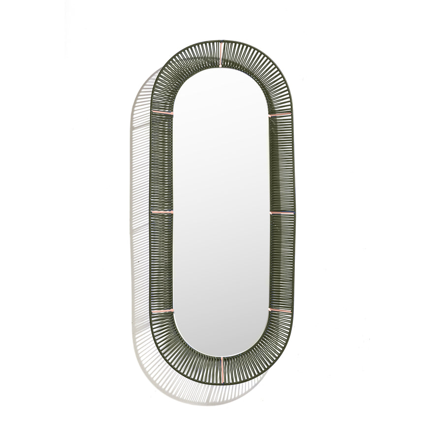 The Cesta Mirror by Ames features an oval design with a woven green frame made from recycled PVC, casting a shadow on its white background. It showcases vibrant color combinations with woven sections linked by thin horizontal bands.