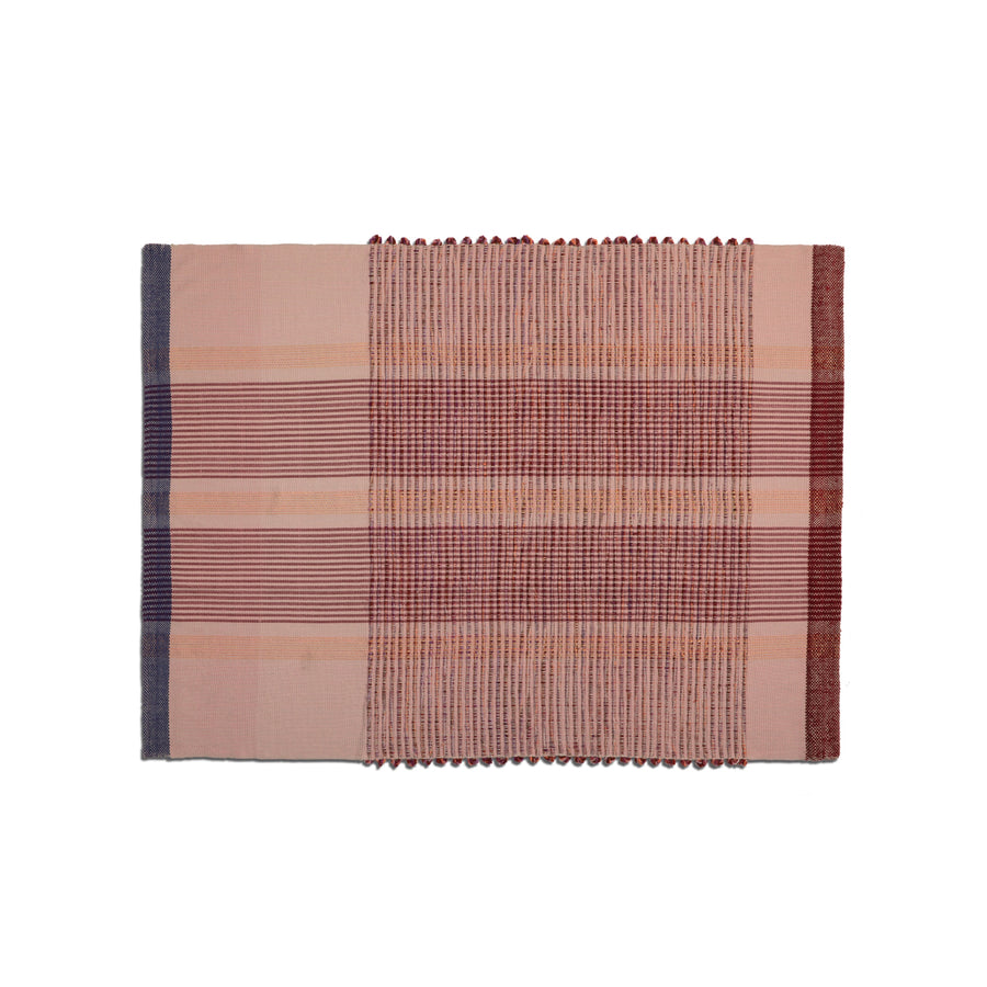 The Chumbes Throws by Ames showcase a rectangular woven textile with horizontal stripes in red, pink, and blue. The plaid pattern includes varying stripe widths and textured sections, reflecting Mae Engelgeers artistry.
