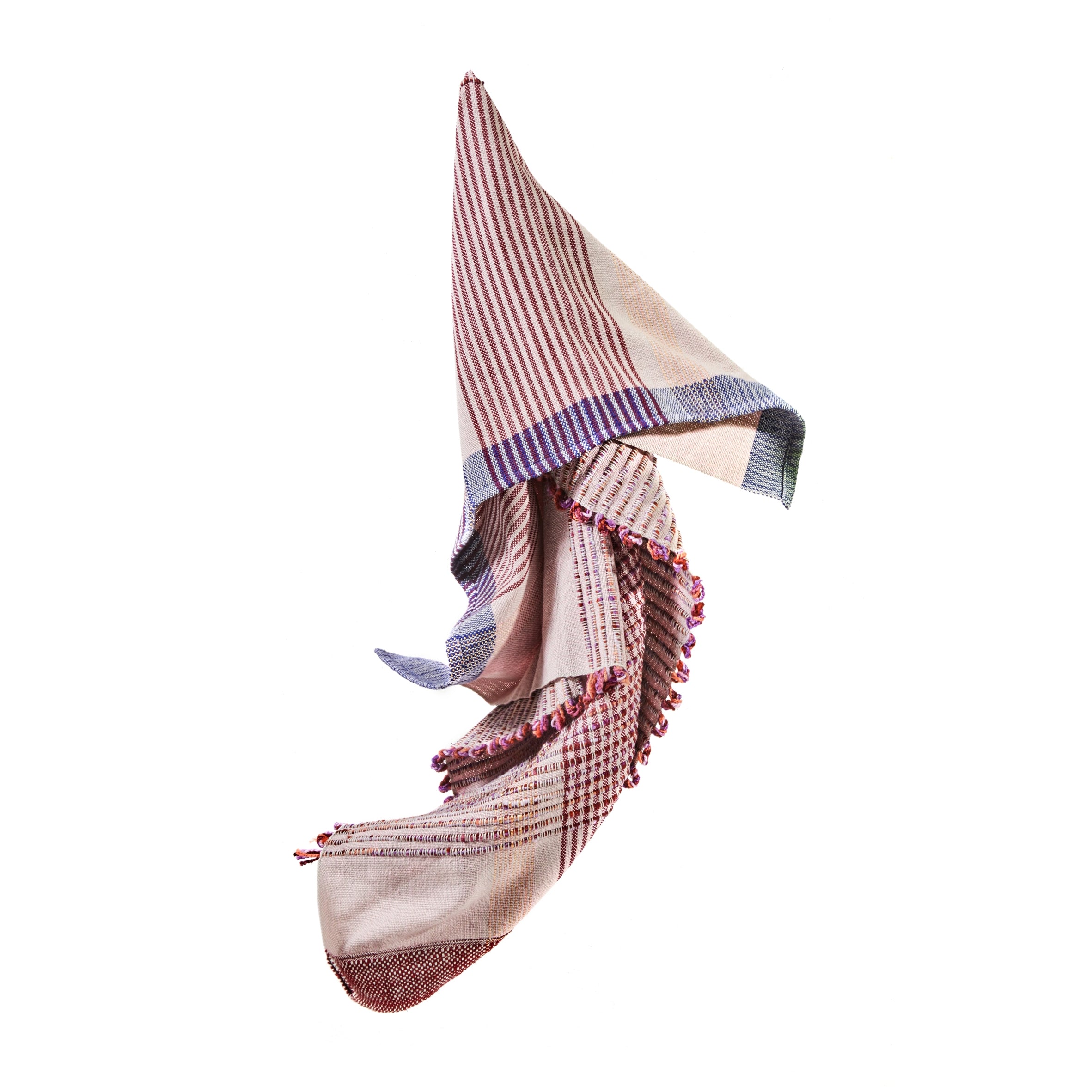 The Ames Chumbes Throws, designed by Mae Engelgeer, exhibit a multicolored plaid pattern with red, blue, and cream stripes and checks. Featuring soft folds against a white background, the edges are adorned with small tassels.