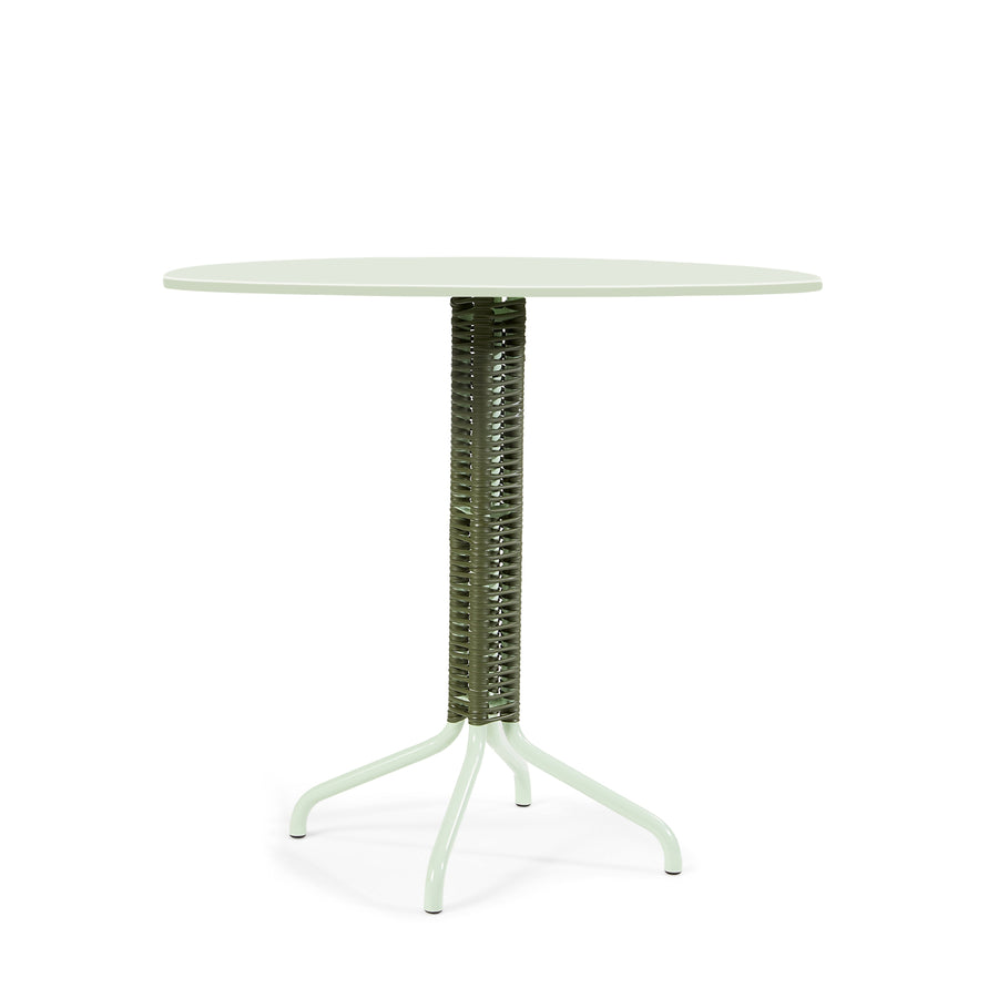 The Cielo Bistro Table by Ames, designed by Sebastian Herkner, showcases a round, pale green top and a textured cylindrical support with four slim, splayed legs, offering a modern aesthetic perfect as a bar or accent table.